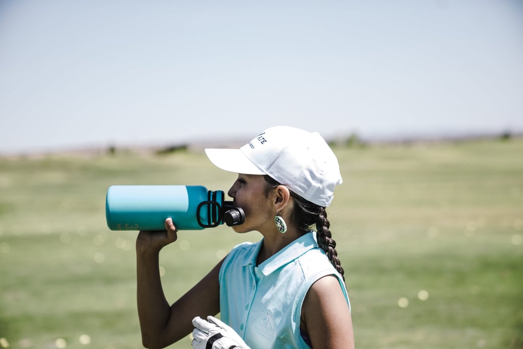 photo-woman-drinking-at-blue-sports-bottle-outdoors