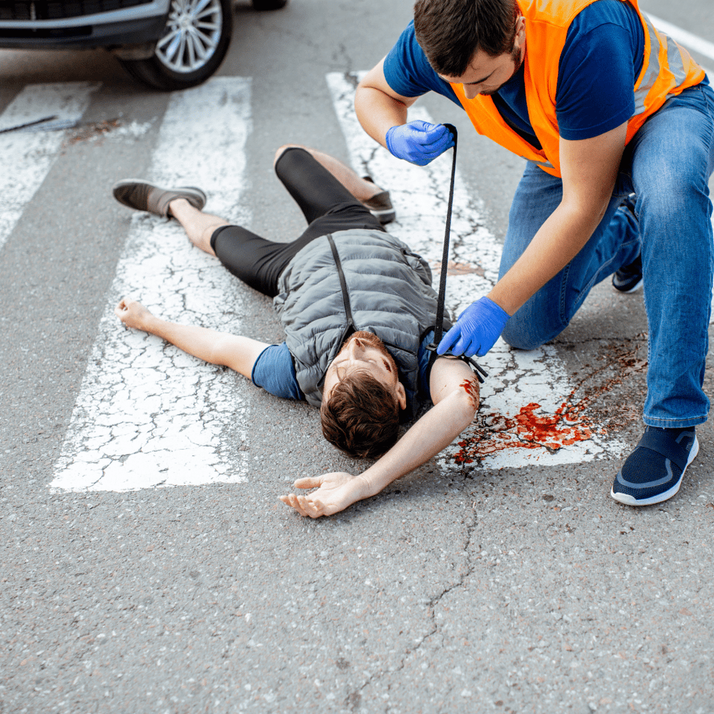 man tying person's arm to stop bleeding after being hit by car