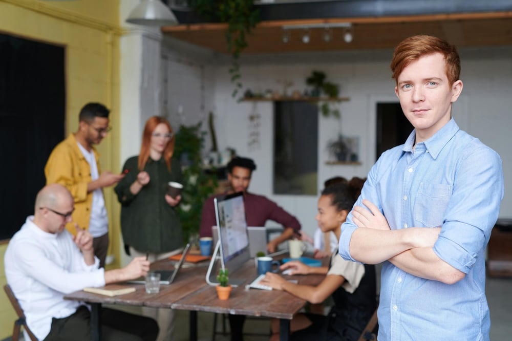 Employee in the foreground looking at the camera with a group of employees meeting in the background