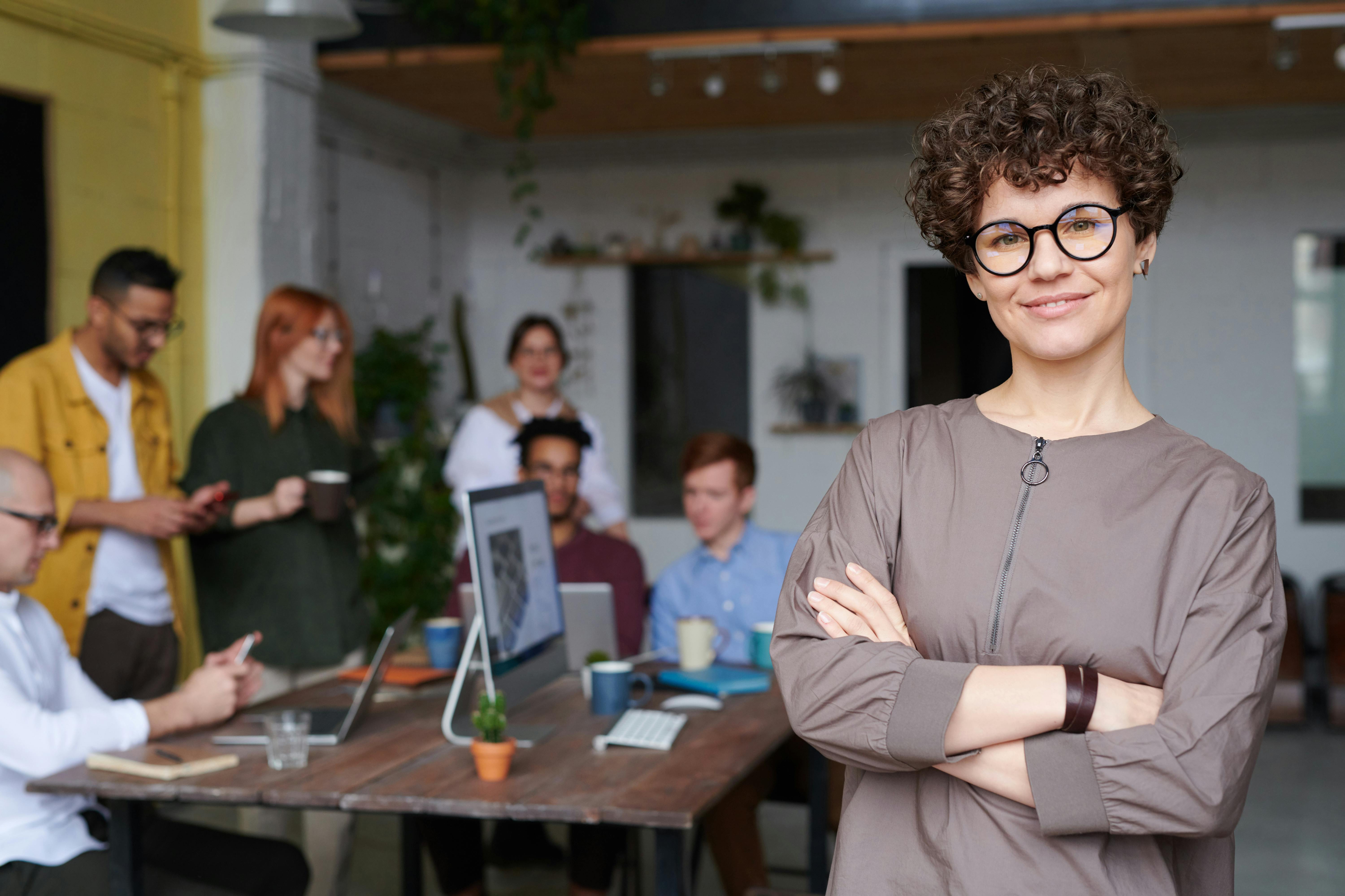 instructor smiling at camera with employee group meeting in the background