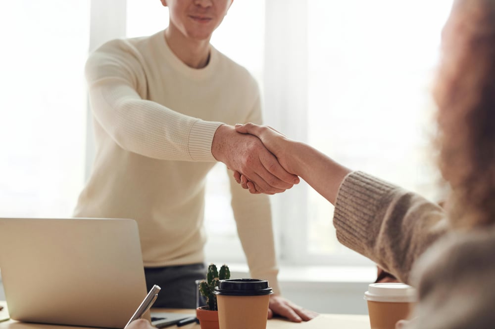 two employees at a desk shaking hands
