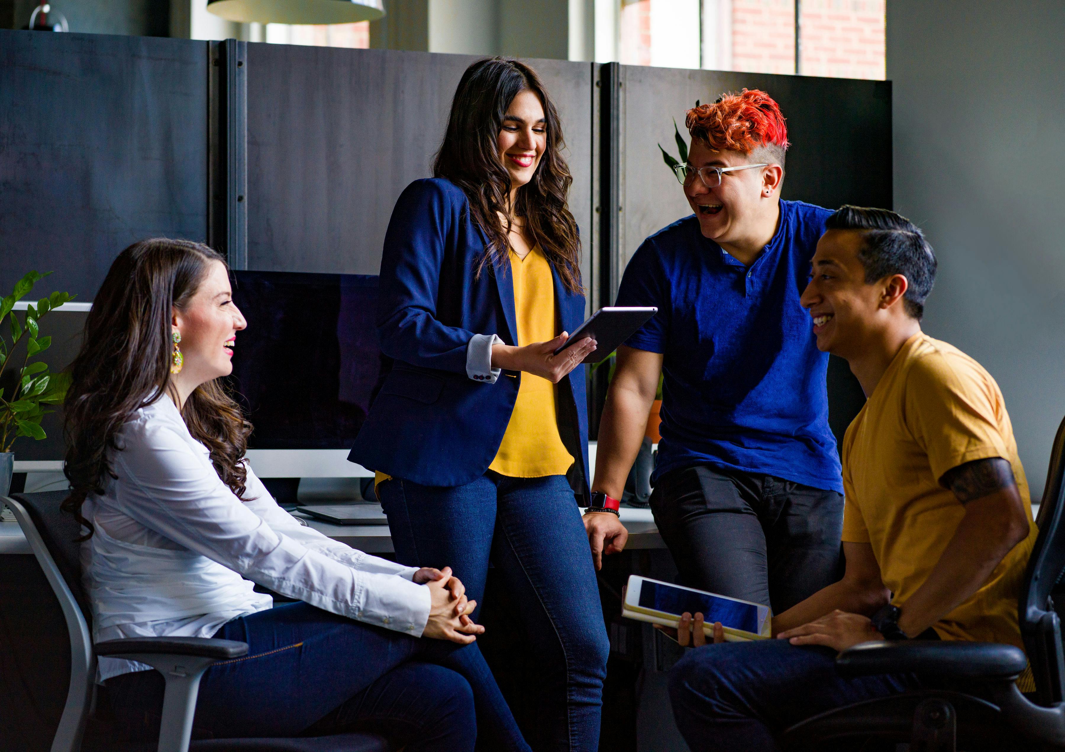 Diverse team of employees collaborating and laughing together in a modern California workplace — representing a safe, positive work environment supported by SB 553 compliance.