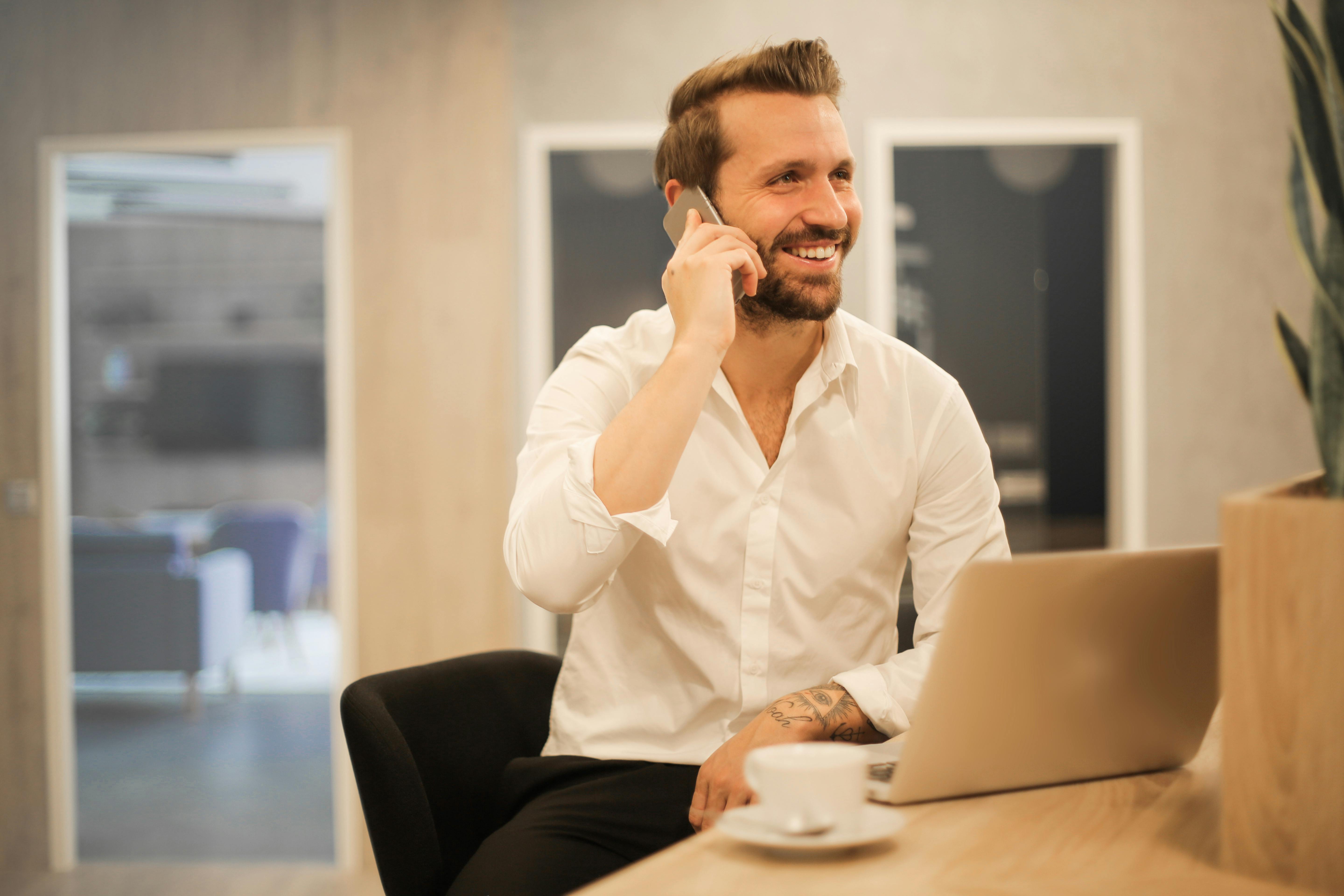 business owner on cell phone with laptop and coffee